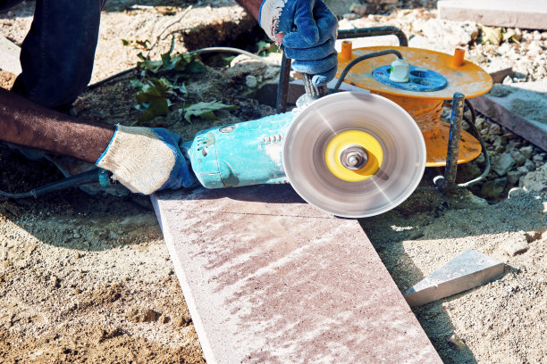 路面施工工人用角磨机切割瓷砖的手图片下载