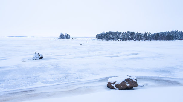 冬天的风景。雪覆盖了海湾上的冰和地平线上的一座岛屿。图片下载