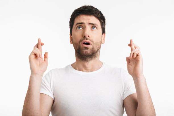 30多岁的男子穿着休闲t恤祈祷，手指交叉，许愿图片下载