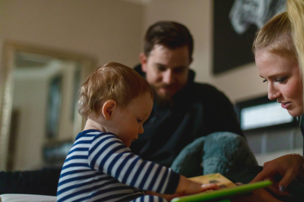 爸爸、妈妈和儿子的小家庭在床上一起读睡前故事系列照片图片下载