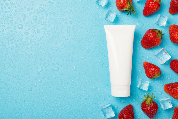 顶部视图照片分散的草莓，冰块，水滴和白色管没有标签在孤立的浅蓝色背景与copyspace在左边图片下载