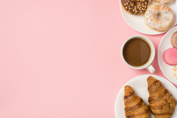头顶照片的各种糕点釉面甜甜圈，牛角面包，马卡龙和一杯咖啡孤立在粉红色的背景与空白空间图片下载