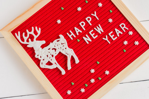红色毡信板上的文字新年快乐和白色背景上的白鹿和糖弹簧。冬季节日贺卡图片下载
