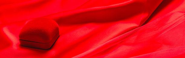 红色薄纱织物上有一个小盒子，上面有一个钻石戒指。结婚的概念图片下载