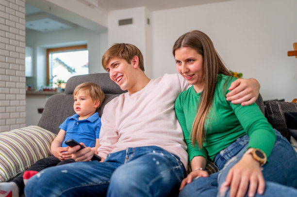 年轻的一家人坐在沙发上看电视图片下载