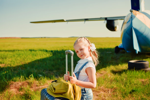 停机坪上一个小女孩提着一个手提箱准备坐飞机旅行。图片下载