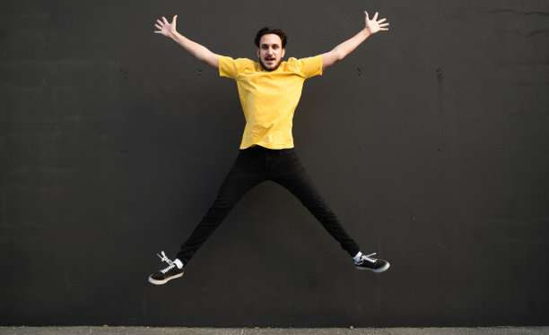 欢快的男子在黑色背景下跳跃。图片下载