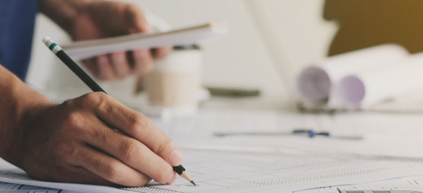 特写镜头:工程师手绘蓝图，使用建筑设备，与合作伙伴和工程工具在工作场所。工程工具和施工概念。图片下载