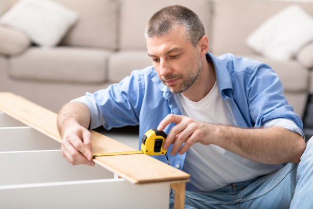 一个成熟的男人在家用卷尺组装货架图片下载