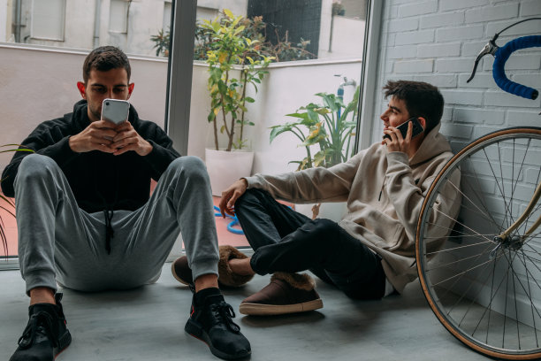 年轻人拿着手机坐在家里的地板上图片下载