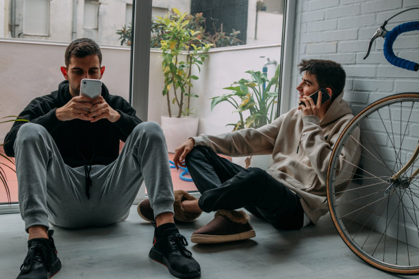 年轻人拿着手机坐在家里的地板上图片下载