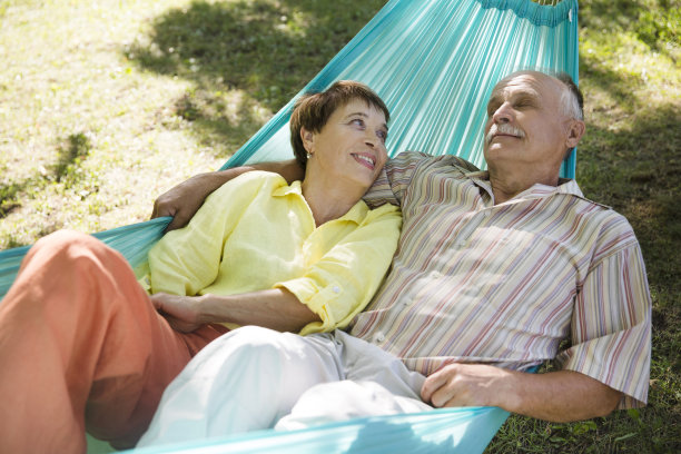 快乐的老夫妇在夏季公园或花园的吊床上休息。友好家庭的概念。图片下载
