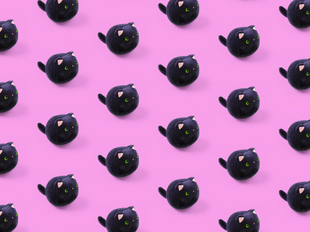 柔软的儿童玩具毛绒绒的黑猫图案以粉红色为背景。图片下载