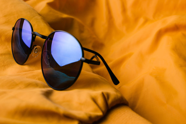 一套时尚的服装和配饰，红色运动鞋和蓝色太阳镜上的黄色夹克作为背景。图片下载