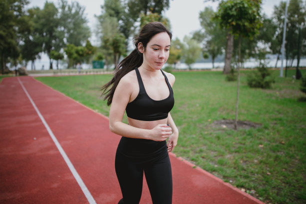 年轻女子在操场上锻炼做运动图片下载