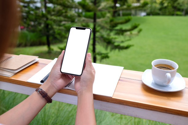 一名女子在户外手持并使用带有白屏的手机图片下载