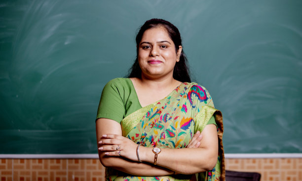 自信微笑的印度学校老师站在教室的黑板前图片下载