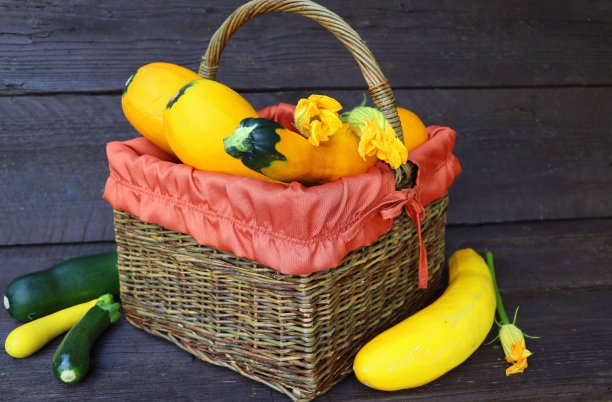 新鲜的西葫芦放在篮子里。旧木桌上放着花西葫芦图片下载