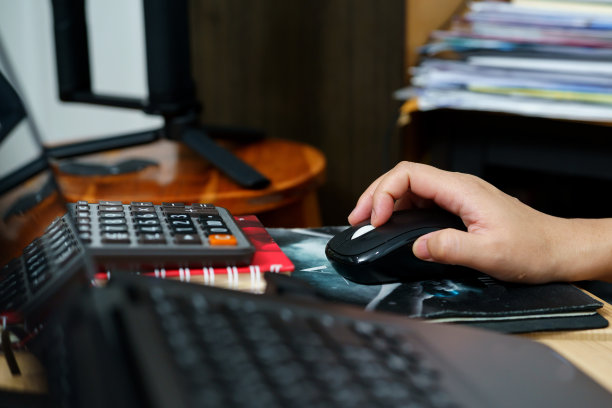 一个女人的手拿着一个黑色的鼠标来操作电脑。图片下载