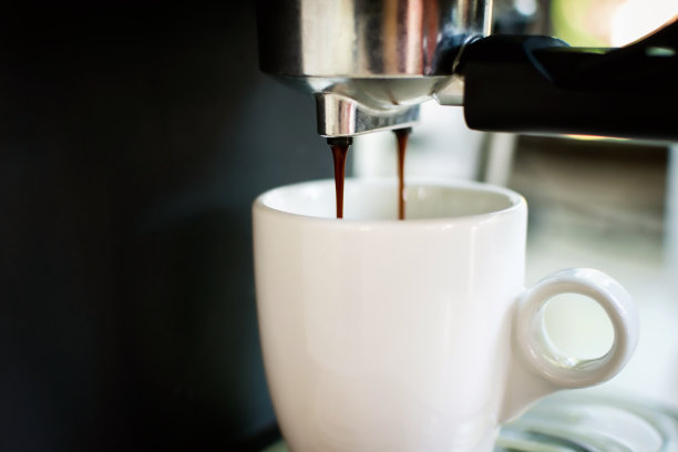 咖啡机将热咖啡倒入咖啡杯。图片下载