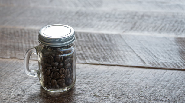 玻璃瓶里的咖啡豆，旧木地板图片下载