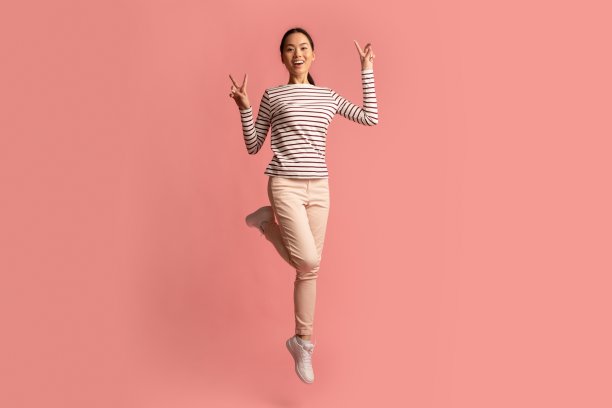 快乐的韩国女性腾空而起，展示和平的姿态图片下载