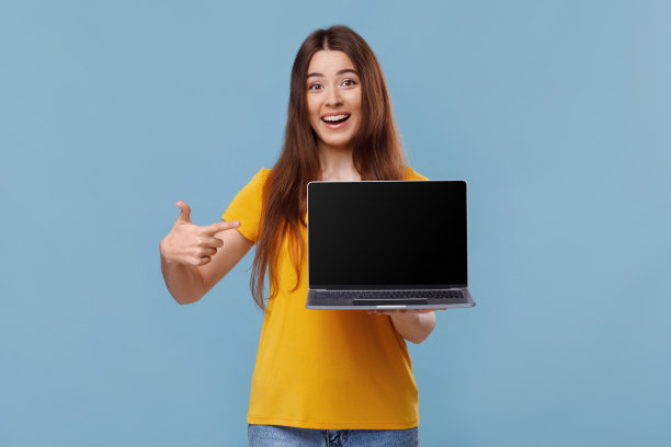 快乐的年轻女士指着空屏幕的笔记本电脑图片下载
