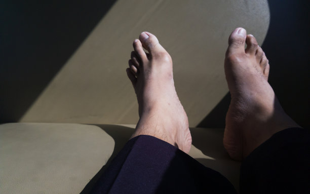 亚洲男人的脚搁在沙发上，阳光照在沙发上图片下载