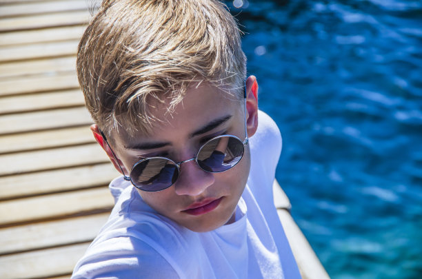 英俊的少年，15-18岁，透过太阳镜看着。图片下载