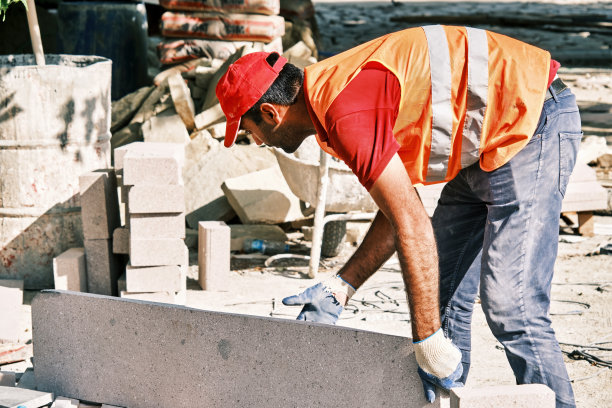 路面施工工人抓着一大块铺路石。图片下载