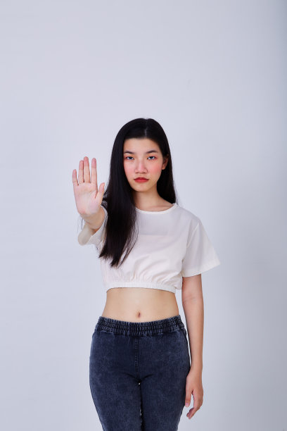一个严肃的年轻亚洲女人的肖像显示停止手势，她的手掌孤立在灰色的背景图片下载