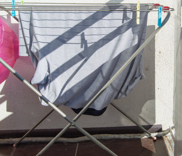 洗过的男t恤挂在阳台的金属烘干机上，阳光明媚，天朗气清图片下载