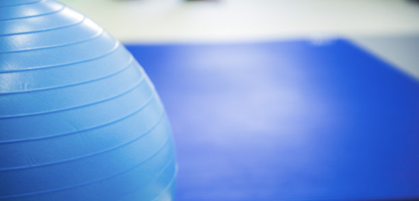 在健身或康复中心的蓝色瑜伽垫上进行健身锻炼的哑铃和健身球。图片下载