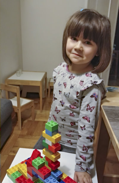 女孩用玩具砖搭起一座塔图片下载