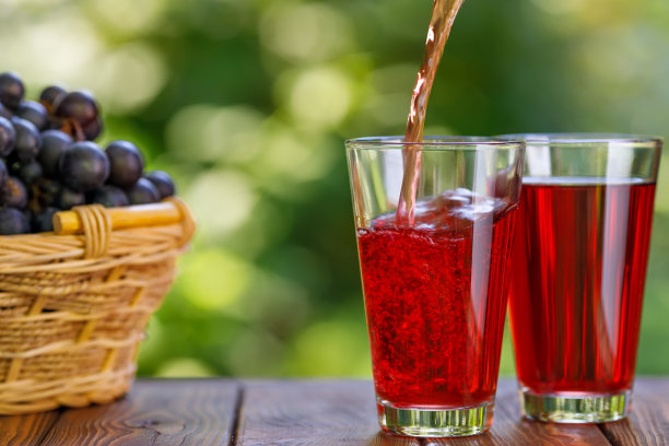 葡萄汁倒进花园桌上的玻璃杯里图片下载
