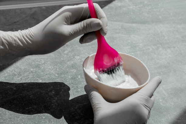 女孩戴着白色橡胶防护手套，手里拿着刷子，混着染发剂，在家里染发图片下载