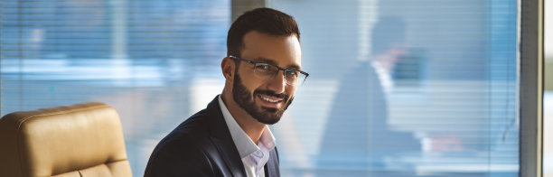 戴着眼镜的快乐男人在桌上用笔记本电脑工作图片下载