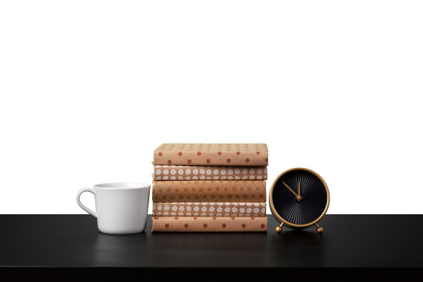 白色背景下，桌上摆放着闹钟、一叠书和杯子图片下载