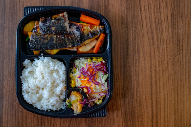 热腾腾的米饭、酱油烤沙巴鱼和蔬菜沙拉装在一个塑料盒里图片下载