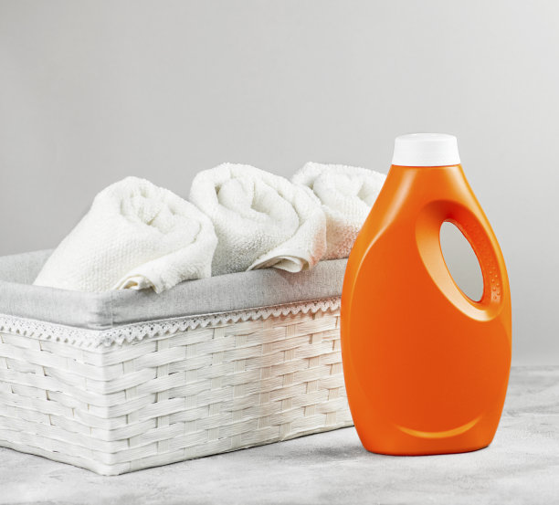 白色毛巾布毛巾放在篮子里，灰色背景上有洗涤剂。图片下载