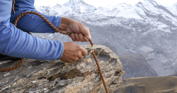 男子在山脊上割断登山绳索图片下载