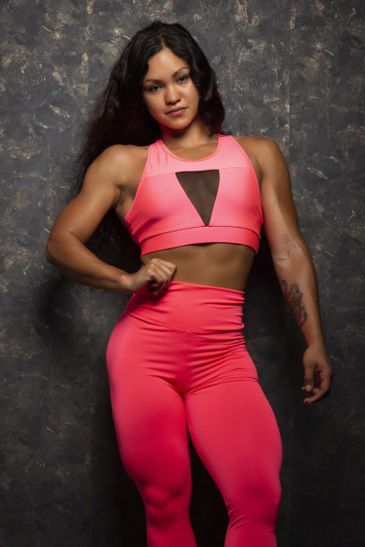 美丽的年轻女性健美运动员在紫红色运动服摆姿势图片下载