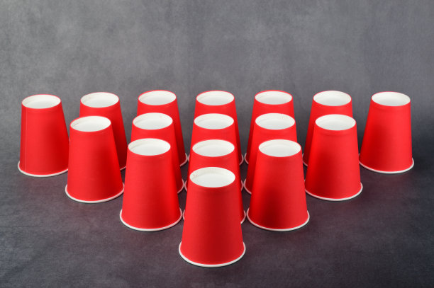 红色纸杯在水平面上排成箭头。图片下载