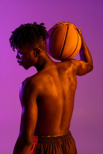 后视图。年轻的非洲人，篮球运动员与球孤立在梯度紫色霓虹灯背景。图片下载