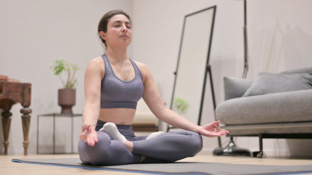年轻的印度女子在瑜伽垫上冥想图片下载