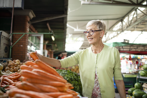 高加索妇女的肖像购买新鲜的有机蔬菜和水果在市场和持袋的健康食品。图片下载