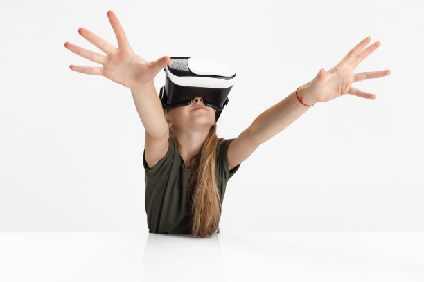 一个聪明的白人女孩在学校戴着虚拟现实眼镜孤立在白色的工作室背景。图片下载