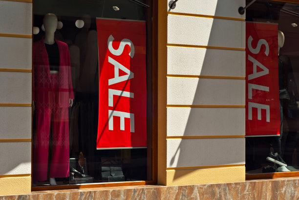 在商店橱窗里做广告的横幅。指示牌在玻璃后面。黑色横幅上的铭文出售。图片下载