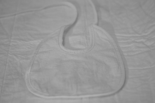 床上的白色婴儿围嘴(欧洲，意大利，马尔凯)图片下载