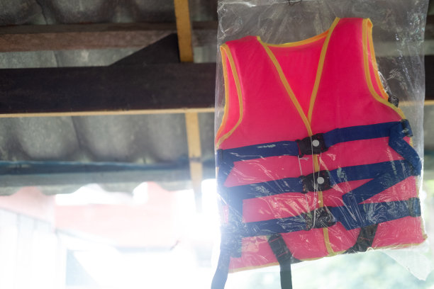 家里挂着一件橙色的救生衣和一条蓝色的腰带。个人漂浮设备图片下载